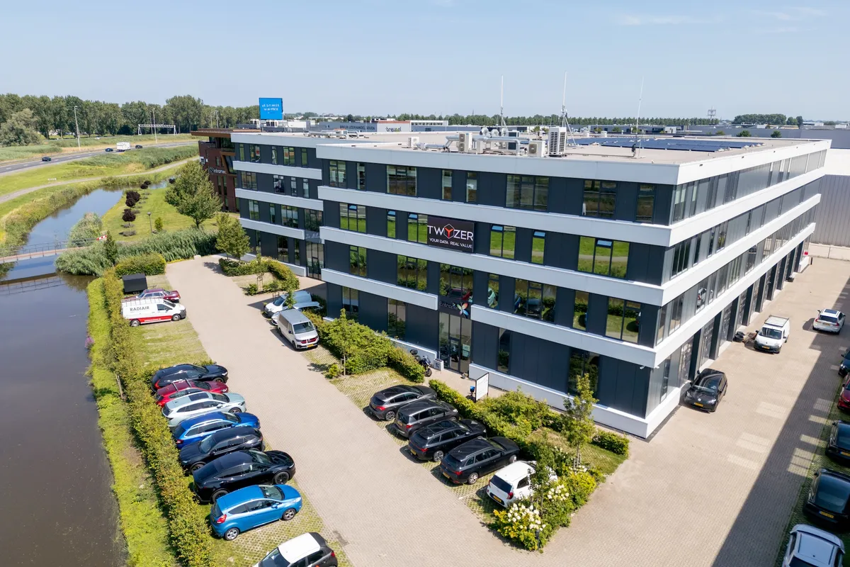 Twyzer hoofdkantoor luchtfoto Luchtfoto van het Twyzer-kantoor met slogan Your Data. Real Value. op de gevel, omringd door groen en parkeerplaatsen